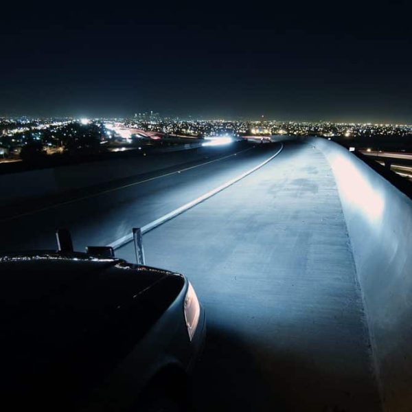 A police car at work at night on a highway bridge.